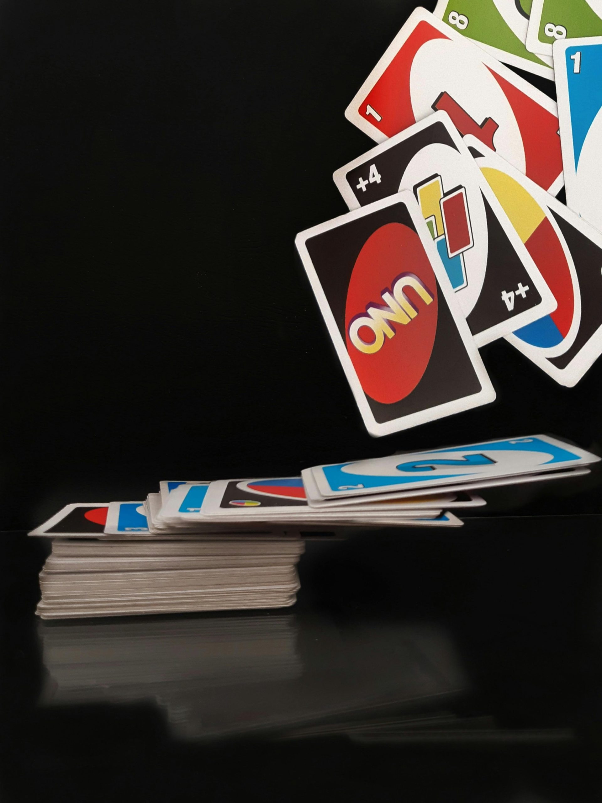 A dramatic view of UNO cards flying mid-air on a black background, capturing the essence of playtime.
